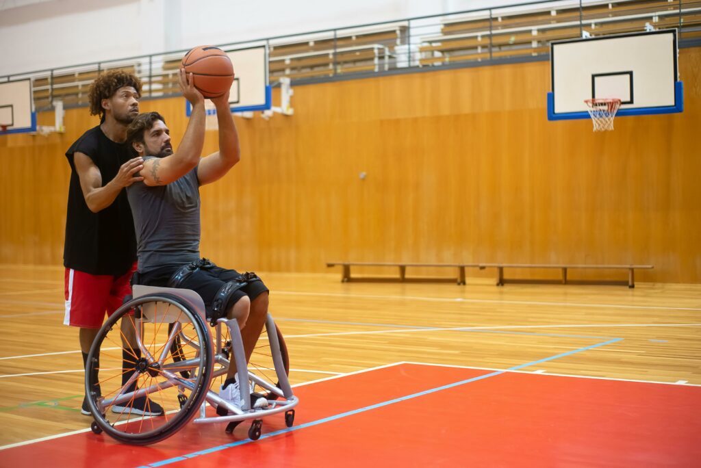 un educateur sportif apa aide un homme en fauteuil roulant pour tirer dans un panier de basketball