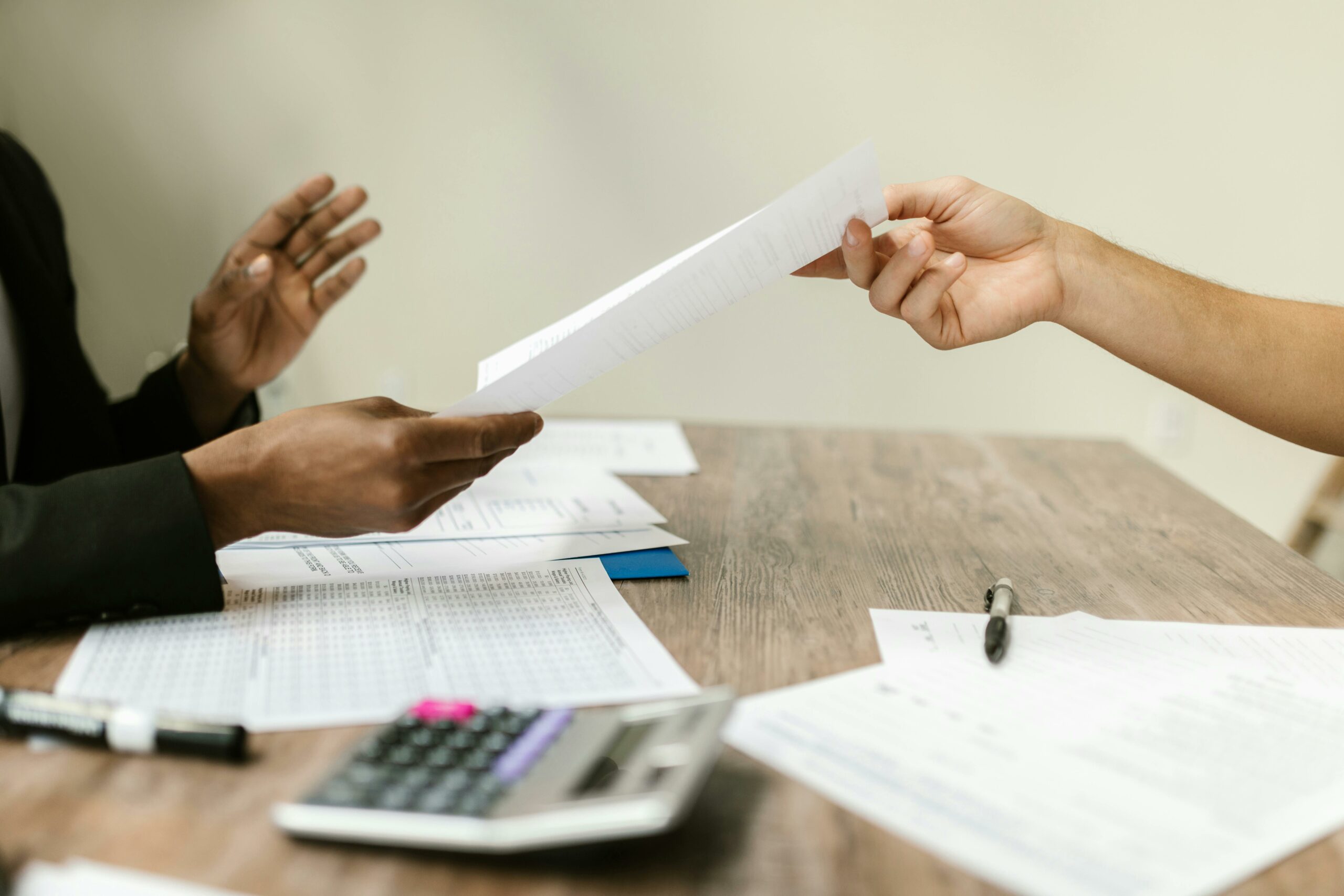 a propos - une main tend une feuille vers une autre personne dans un bureau